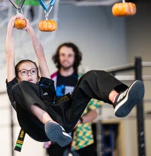 Girl swinging from pumpkin grips on the course
