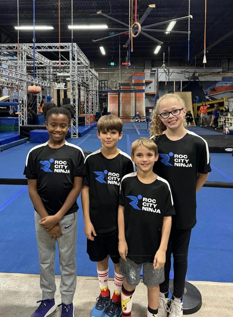 Four kids in ROC City Ninja shirts in front of the course