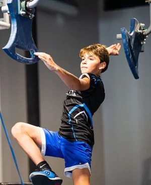 Boy leaping between hanging grips